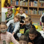 Zdjęcie zostało zrobione w bibliotece CKiB w Opalenicy. Na kolorowym dywanie siedzą dzieci.