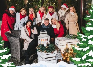 Zdjęcie Opalenickiej Grupy Wokalnej. Na zdjęciu jest 9 kobiet i jeden mężczyzna. Wszyscy są uśmiechnięci i elegancko ubrani