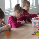 Na zdjęciu dzieci siedzące przy stole i składające budowle z klocków