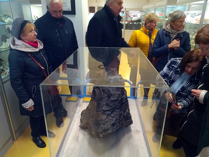 na zdjęciu seniorzy, którzy oglądają jeden z elementów wystawy muzeum (kamień)