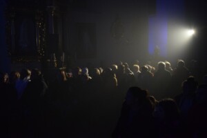 publiczność obecna na występie widoczna w cieniu, częściowo oświetlona padająca smugą światła