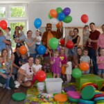 zdjęcie grupowe dzieci i rodziców uczestniczących w zajęciach klubu malucha, wszystkie dzieci trzymają kolorze balony