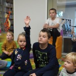 Zdjęcie zostało zrobione w bibliotece CKiB w Opalenicy. Widać na nim dzieci. Dziewczynka ubrana na granatowo na pierwszym planie ma podniesioną rękę.