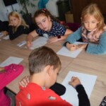 dzieci siedzą przy stole rozwiązując zadania